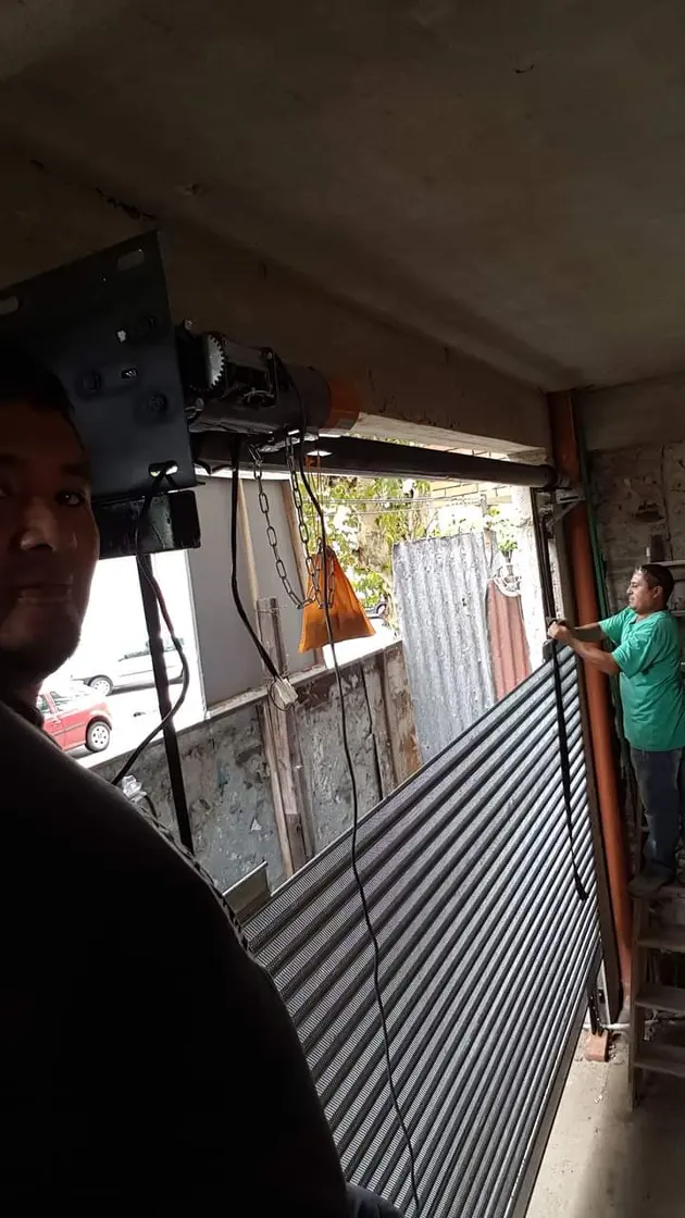 Técnico instalando motor de automatización, foto oscura con persona en primer plano